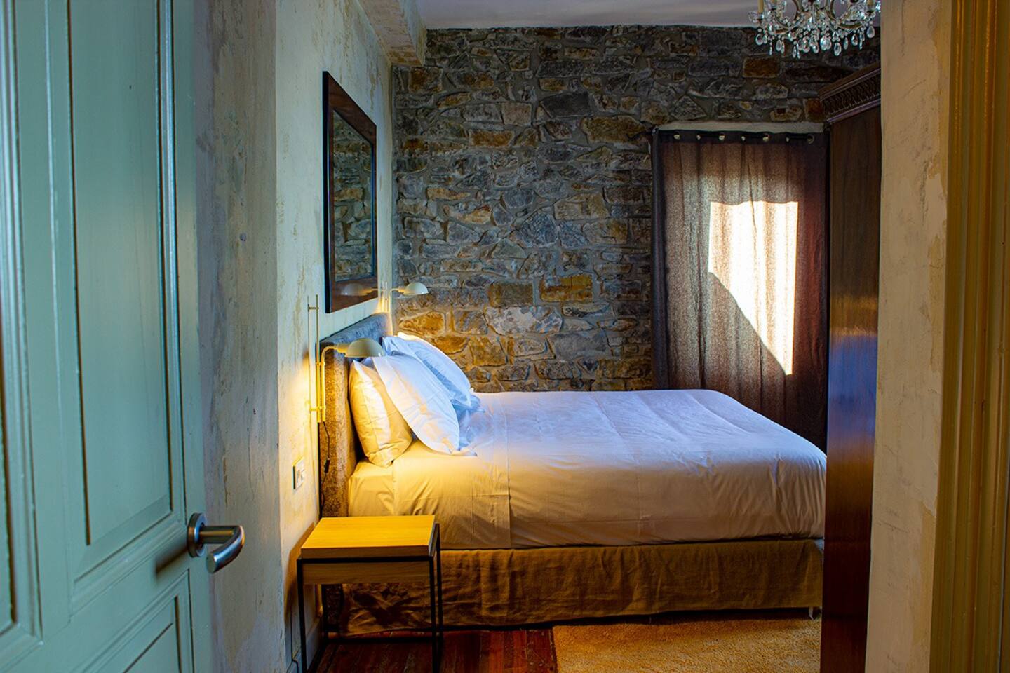 Bedroom with original stone wall and chandelier